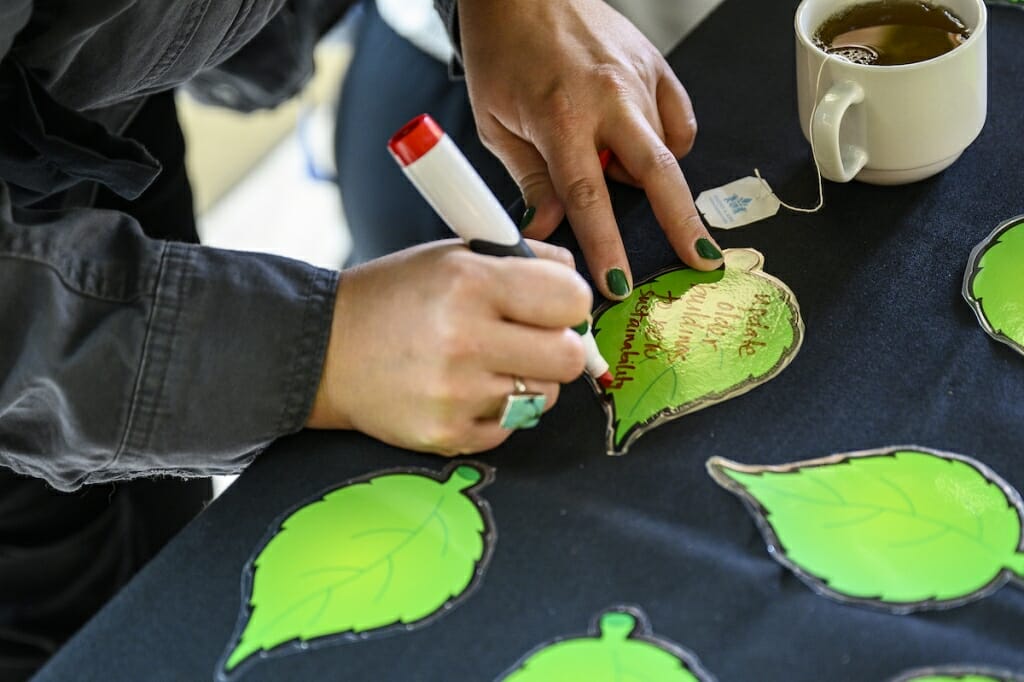 A person uses a marker to write on a plastic leaf.
