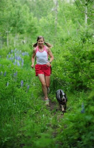 Photo of Aschwanden running through a forest with a dog