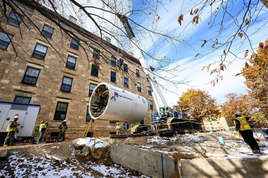 A crane lifts the bore head before lowering it into a hole to begin its tunneling work.