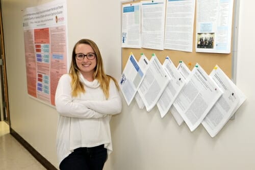 Photo: Kim Drastal standing next to a bulletin board 