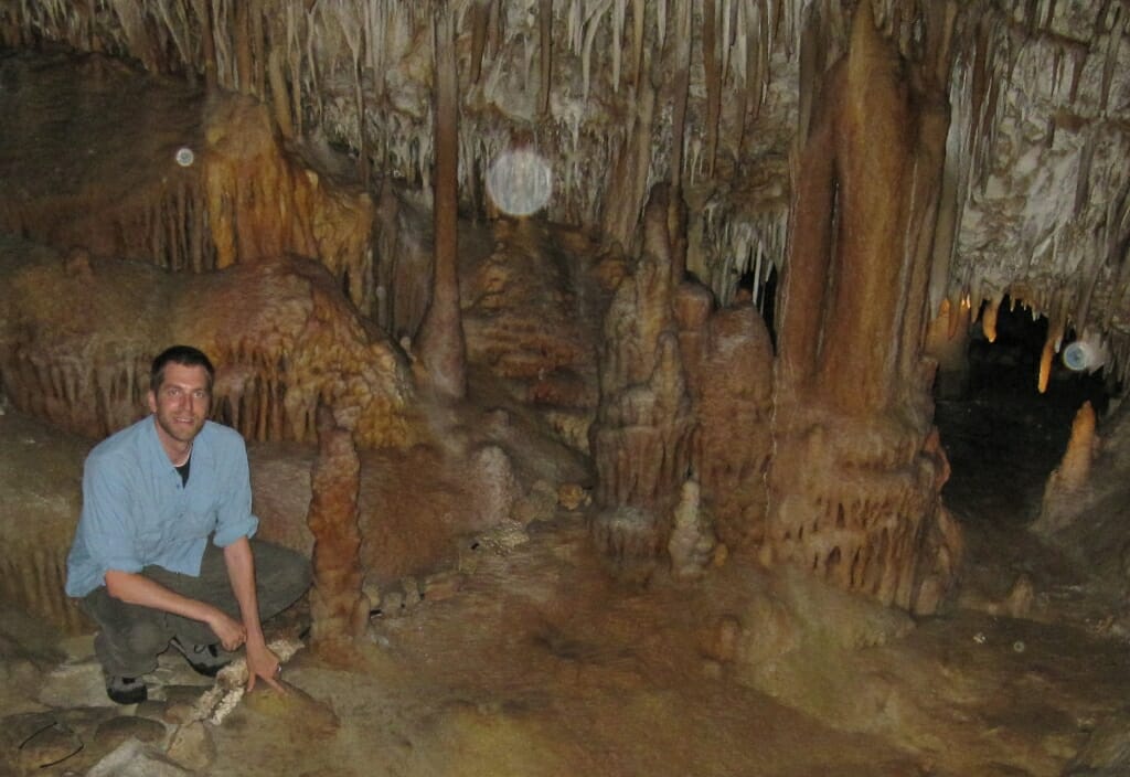 Photo: Ian in a cave, pointing to floor