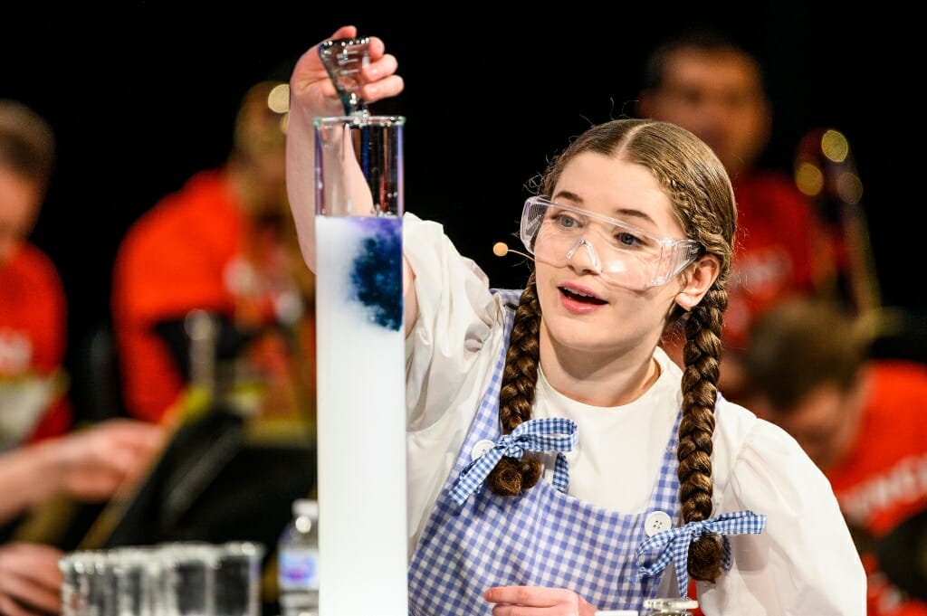 Dorothy, played by Faith Oldenburg, prepares to make a rainbow from monochromatic chemicals.
