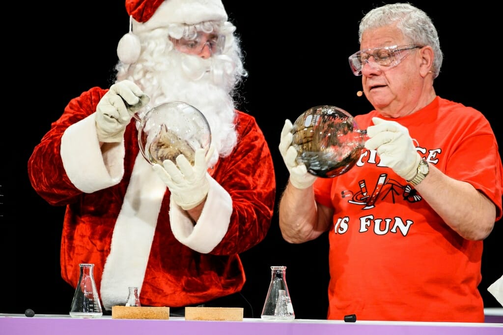Photo of Santa Claus and Shakhashiri shaking round flasks full of chemicals.