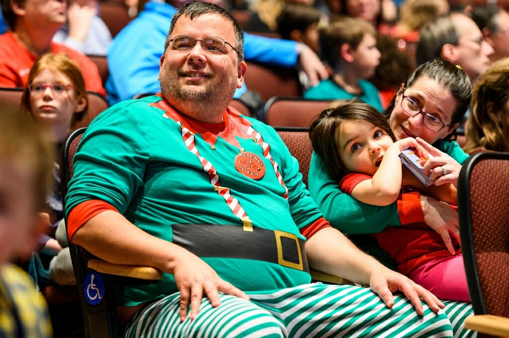 Photo of a father, mother and daughter in red and green elf costumes.