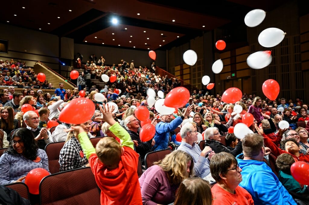 Photo of red and white balloons dropping into the audience.