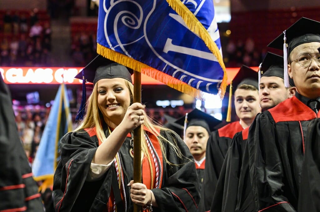 Photo of graduate carrying a flag.