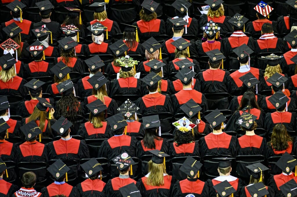 Photo from above of rows of seated graduates in caps and gowns.