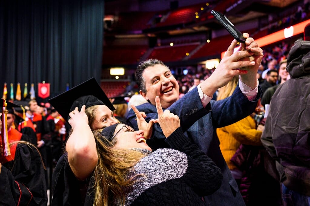 Photo of a father, mother and graduating daughter taking a selfie.