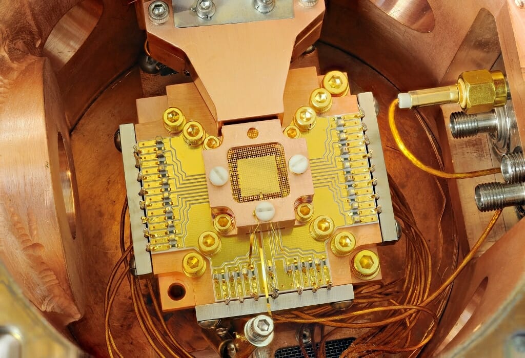 Photo: A square gold chip in surrounded by a copper enclosure and gold wire mesh