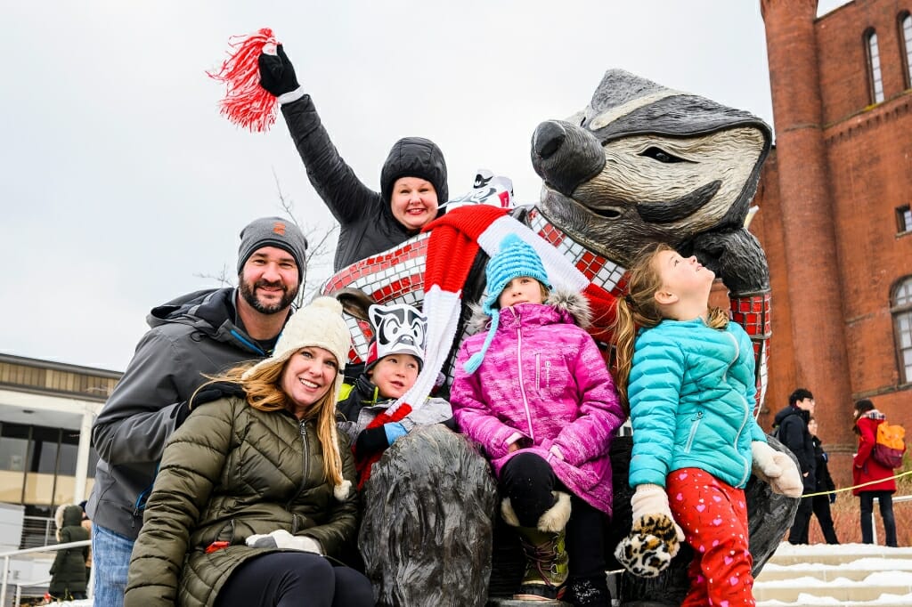 Photo: A family smiles and waves while perched on the Bucky Badger statue.