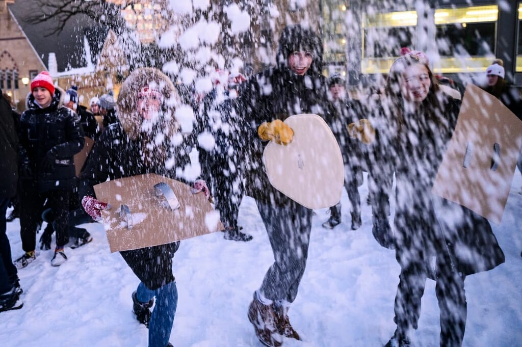 People holding pieces of cardboard, barely visible behind barrage of snowballs