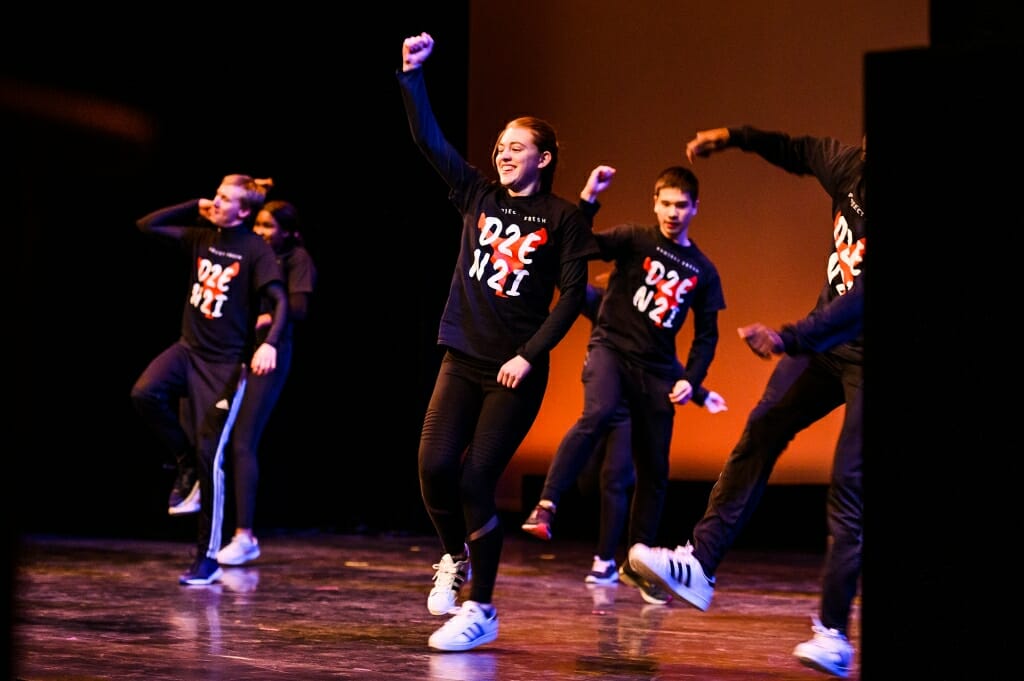 Dancers raise their arms in carefully synchronized choreography.