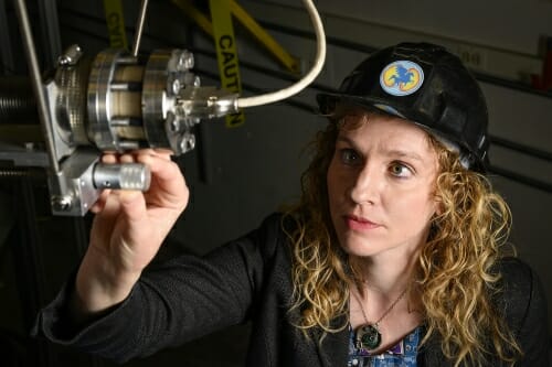 Diem holding part of chamber in her hand. She is wearing a hat with a pegasus logo.