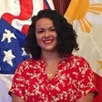 Lenai Johnson standing in front of a Peace Corps flag