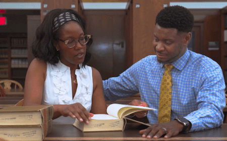 Two people look at a book in the law library.