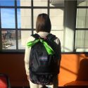 Student wearing a backpack with a green bandana tied to it.