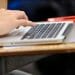 Closeup of a students fingers touching the trackpad on a laptop computer keyboard