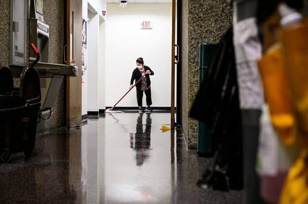 A person mops a floor in an empty room.