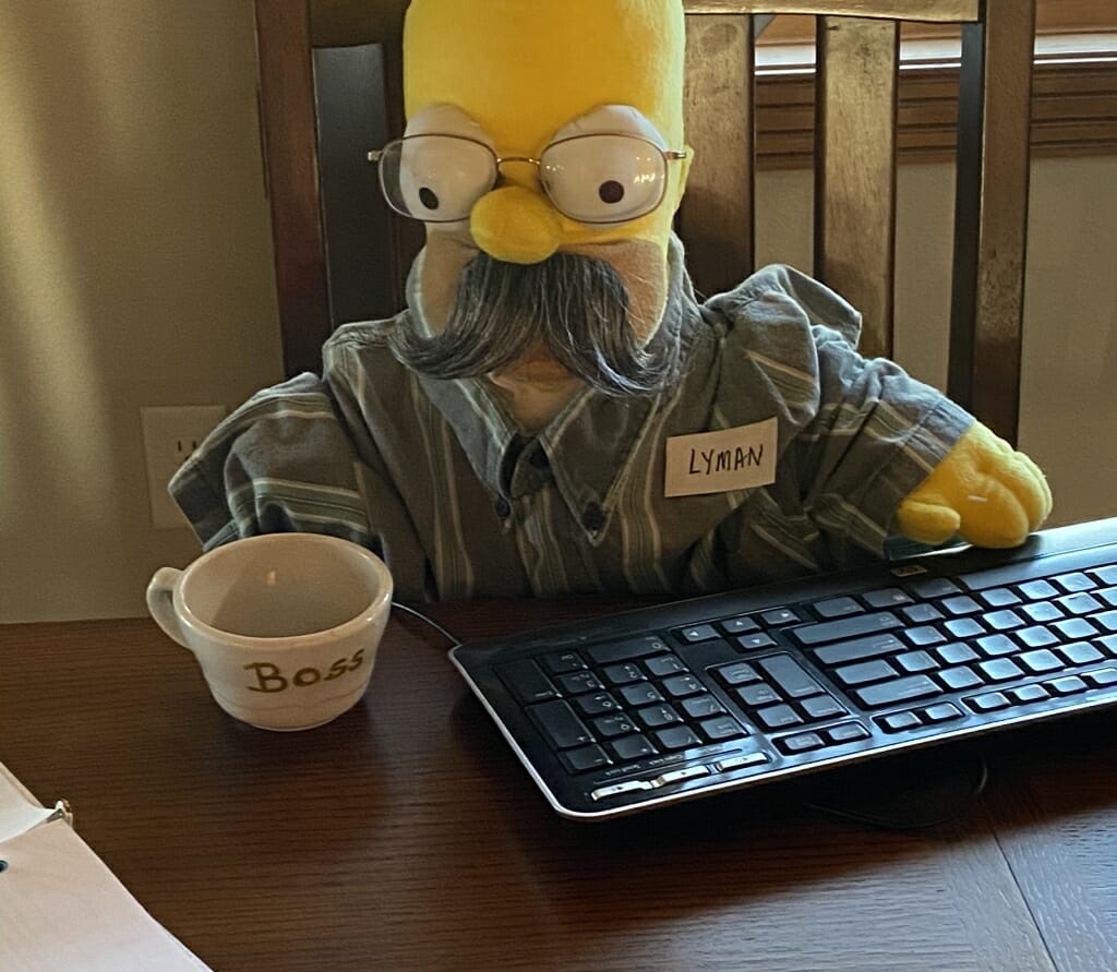Homer Simpson figure posed at a keyboard with a mug that says Boss