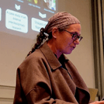 Laurie Beth Clark standing in front of a projection screen