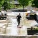 A lone worker scrubs an empty Terrace with a power-washing machine.