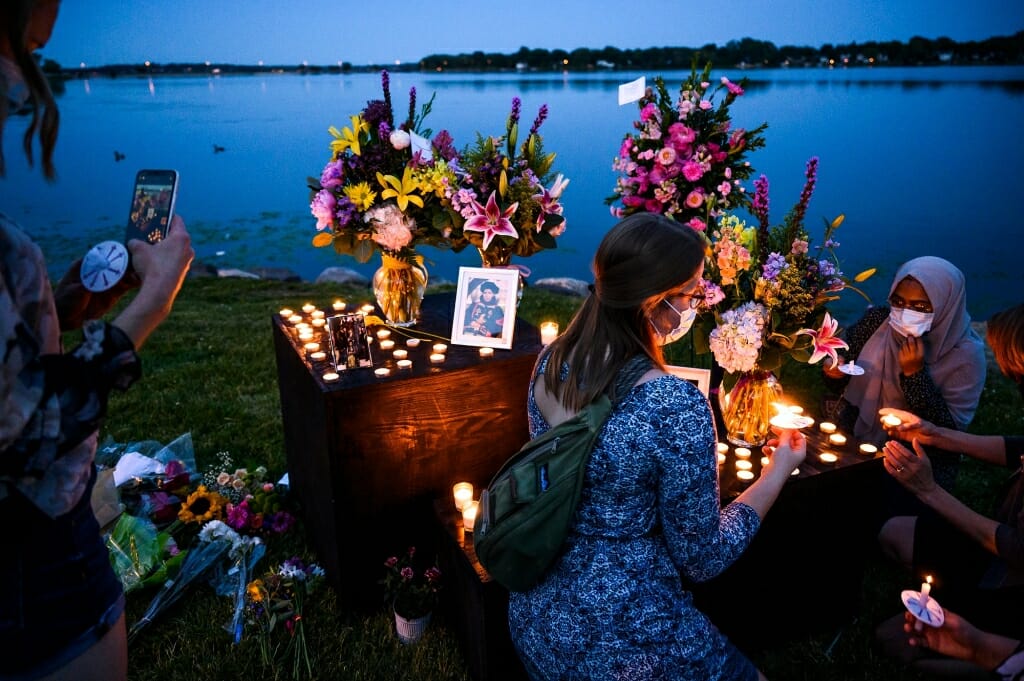 People gather in a lakeside park at dusk.