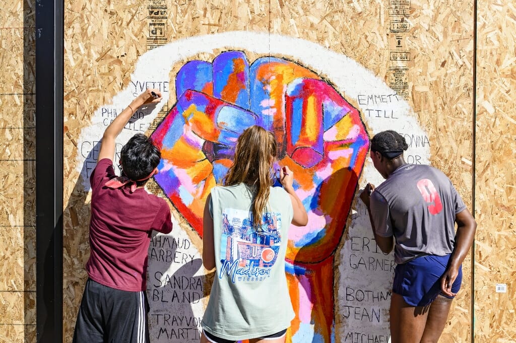 UW-Madison students (left to right) Daniel Ledin, Molly Pistono and Courtney Gorum work together to paint a mural commemorating the names of black victims of police violence throughout the country on a sheet of plywood covering the windows of the Community Pharmacy building on State Street in Madison June 5. The mural is one of many that have been painted on businesses and shops along the street following several nights of protests in response to the killing of George Floyd in Minneapolis.