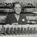 Elizabeth McCoy seated at a lab bench behind test tubes and in front of bottles and jars on shelves
