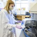 UW student Emma Sweet loads a kingfisher flex automated nucleic acid extractor as part of COVID-19 test preparation.