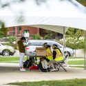 Poll workers wearing personal protective equipment help voters during an early in-person absentee voting session held on Library Mall.