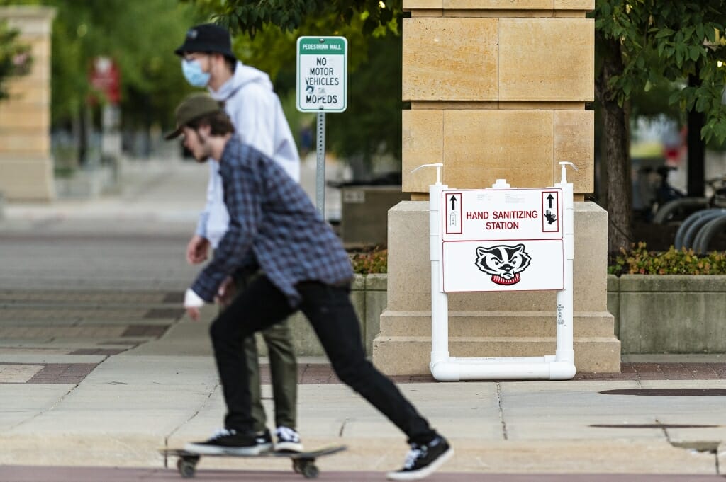 Pedestrians near 333 East Campus Mall pass by a newly installed hand sanitizer.