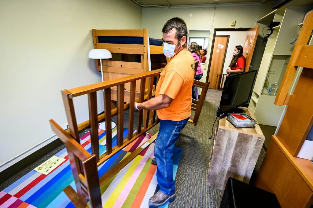 Mark Chrostowski carries a futon frame as he and wife Vicki help their daughter Maggie Chrostowski, standing in the doorway, move in to Elizabeth Waters Residence Hall.