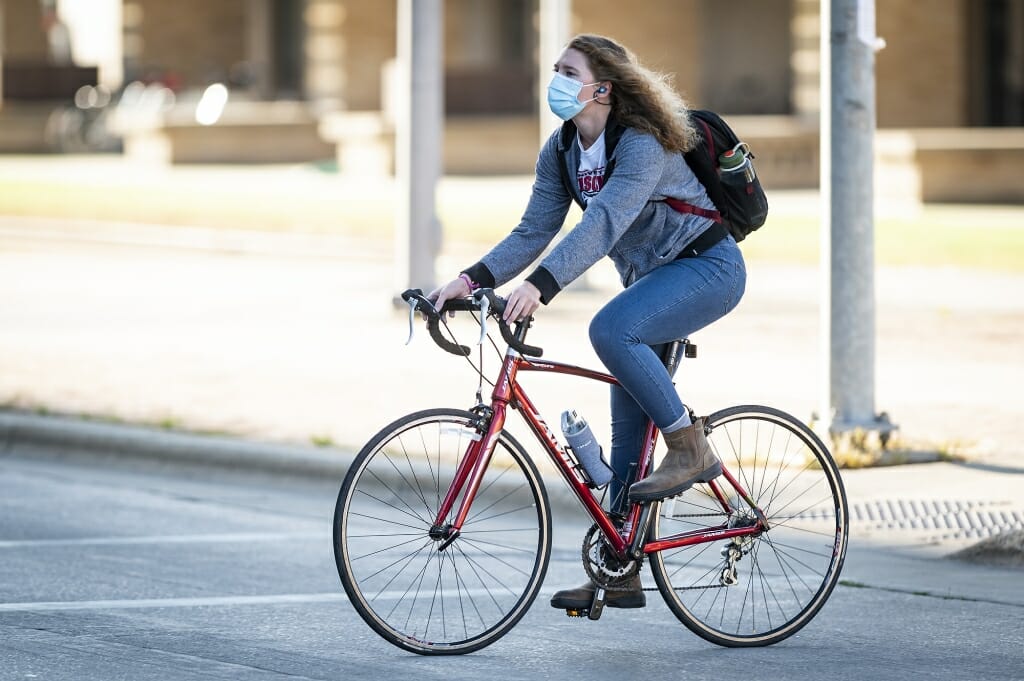 A woman pedals her bike into campus during the first day of classes.