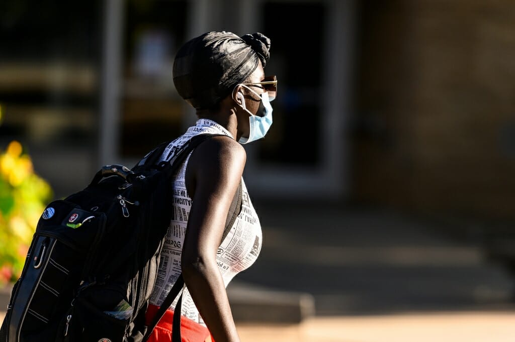 A woman wearing a mask walks along Observatory Drive on the first day of classes.