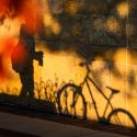 Late afternoon shadows of a parked bike and a passing pedestrian are cast upon the stone exterior of the Gordon Dining and Event Center.