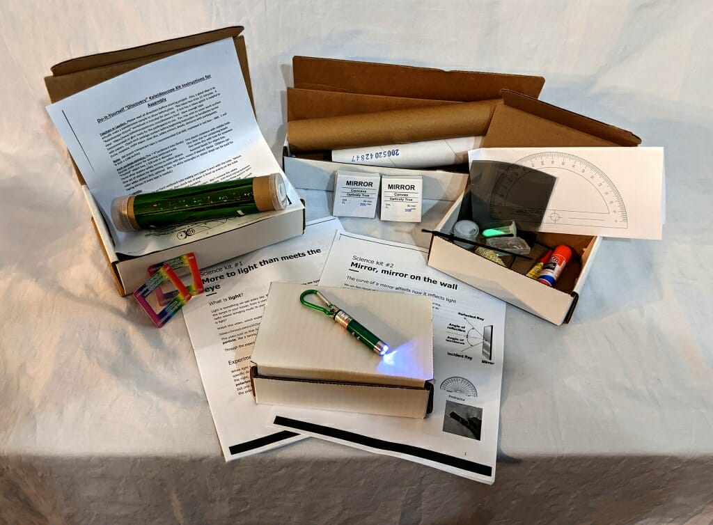 Physics kit items in boxes, including kaleidoscope, flashlight, protractor and instructions