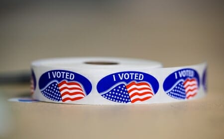 Roll of oval "I VOTED" stickers with American flags on them