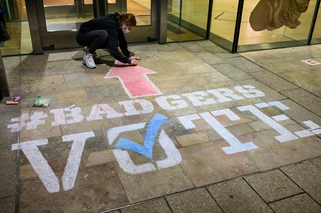 Student Gabi Runde finishes up a stenciled piece that points to the polling place.
