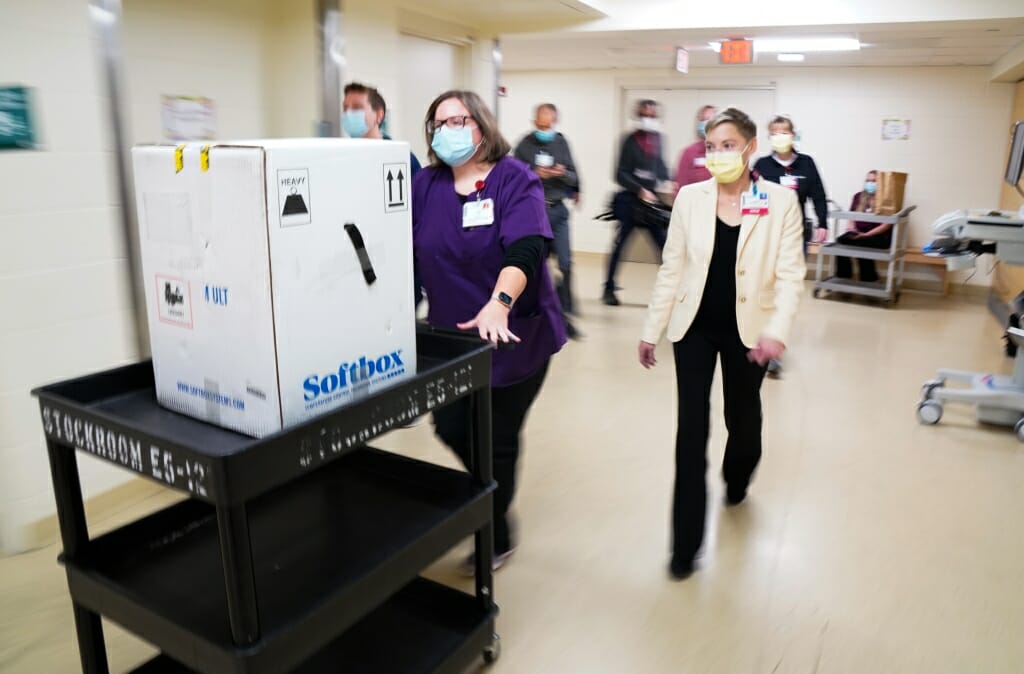 Amy Schultz and Andrea Wipperfuth of UW Health Ambulatory walk the package containing the COVID-19 vaccine down the hall shortly after its arrival.