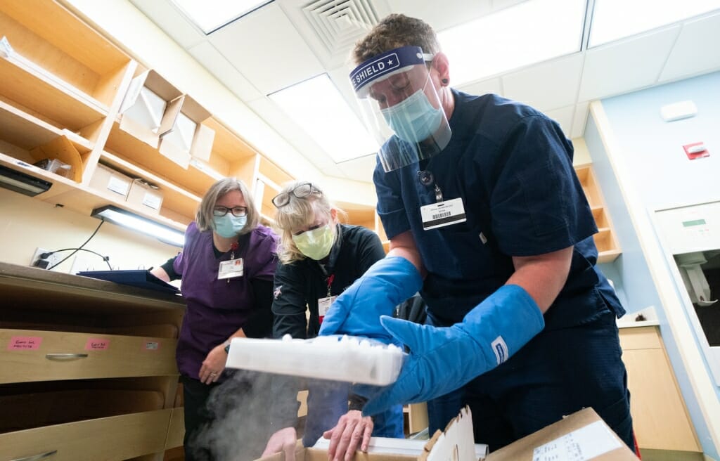 UW Health pharmacy technicians, from left, Amy Schultz, Susan Johnston and Nikolas Gardner unpack a box of Pfizer's COVID-19 vaccine soon after its arrival.