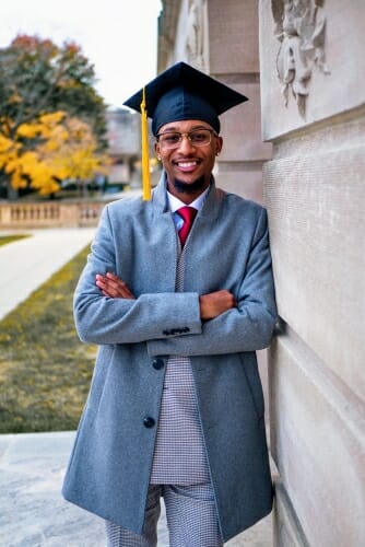 Vershawn Hansen wearing graduation cap and leaning against a building