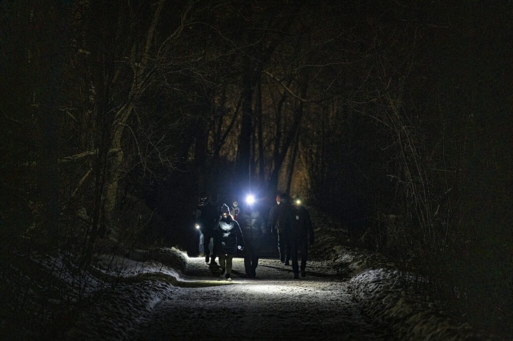 A group of participants wearing headlamps take part in an Outdoor UW night-hike event as they walk down the Howard Temin Lakeshore Path.