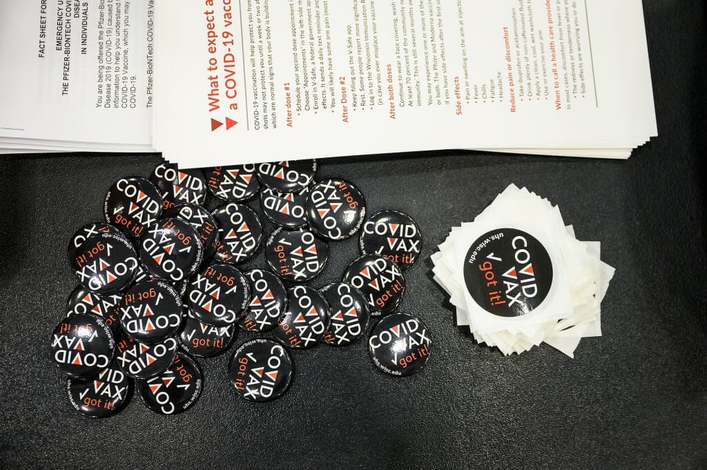 Vaccination buttons and stickers on a check-in table at the vaccination site.