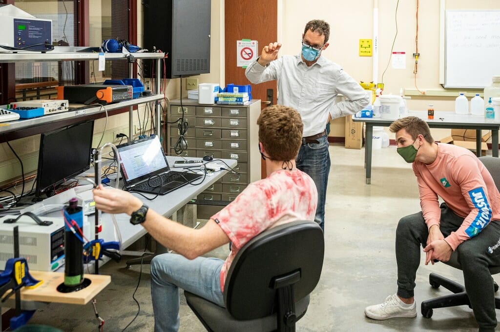 Professor Scott Sanders, standing, discusses a lab project with students Anthony Krotiak (back to camera) and Ben Krimpelbein during Mechanical Engineering 368: Engineering Measurements and Instrumentation, an in-person class and lab taught at the Mechanical Engineering Building on March 8.