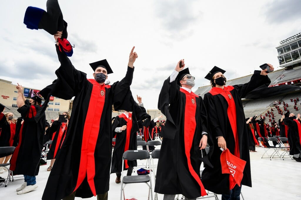 Photo of three graduates jumping along to the music.