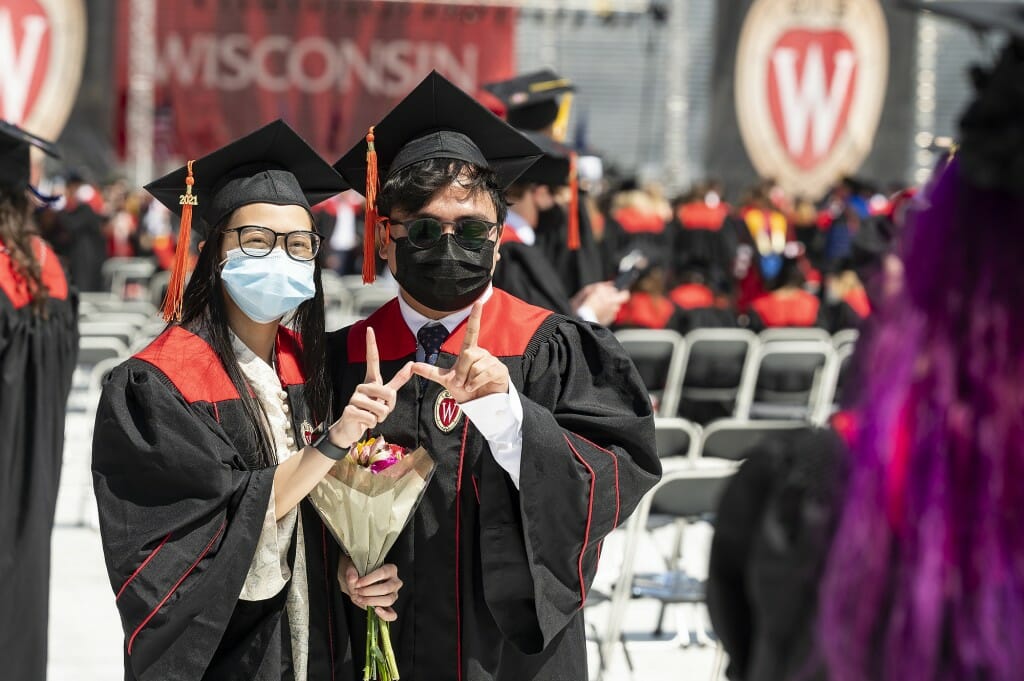 Photo of two graduates flashing the "W" with their hands