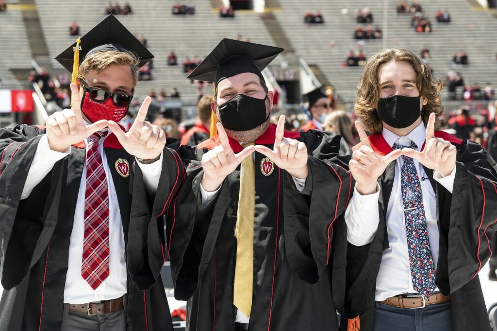 Photo of three graduates flashing the "W"