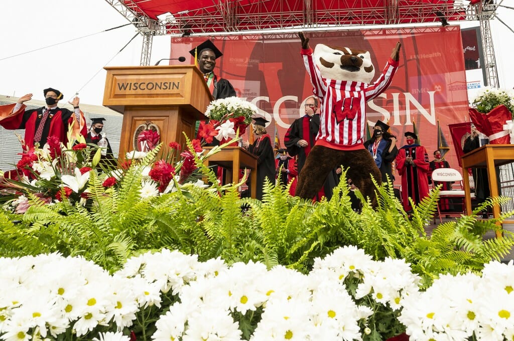 Photo of Mwakatika and Bucky Badger jumping on the stage