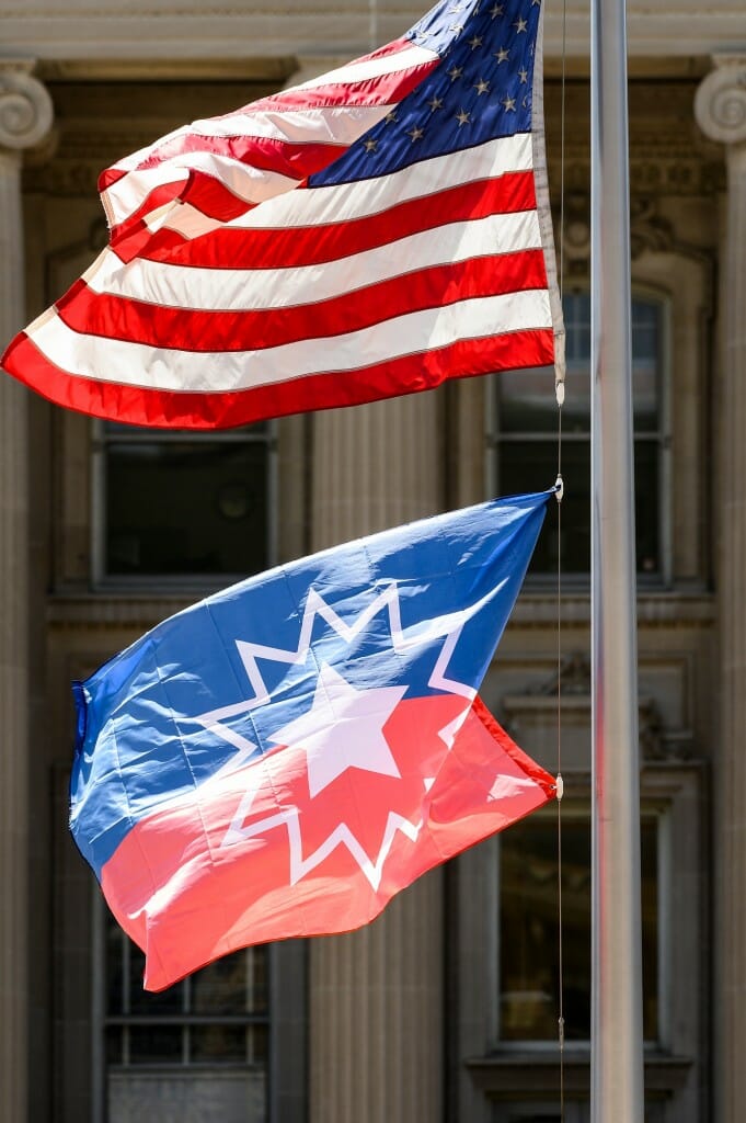 A close-up of the Juneteenth flag and American flag on a flagpole.