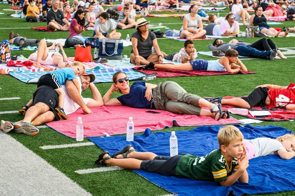 At center, Amber Wersal, a veterinary technician with the Department of Research Animal Resources and Compliance, her husband, Chris, and son, Fritz, 3, relax on a blanket and enjoy the movie.